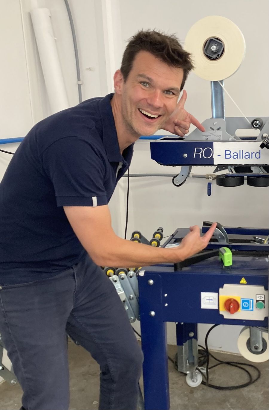 Ro pointing at a taping machine labelled RO Ballard