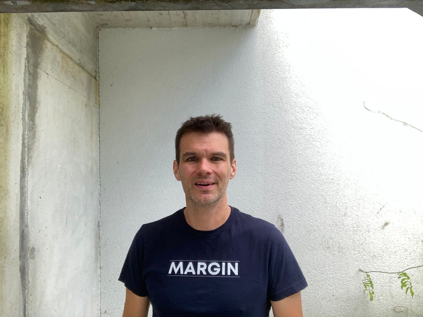 Ro in a navy MARGIN t-shirt against a concrete wall