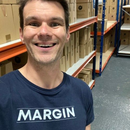Ro grinning in a MARGIN t-shirt in a warehouse